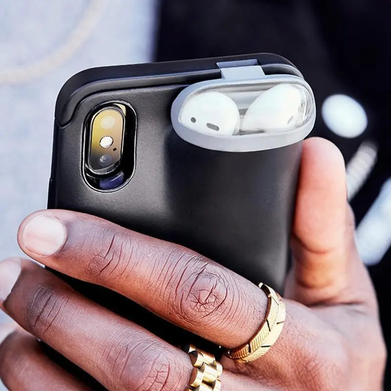 a person holding a cell phone with ear buds in it