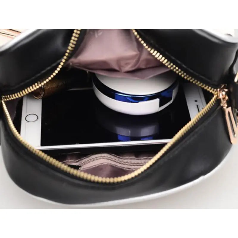 a cell phone inside a black purse with gold zippers