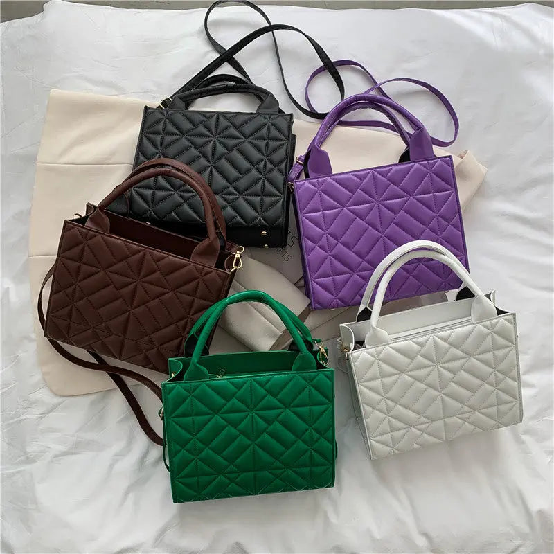 a group of four purses sitting on top of a bed